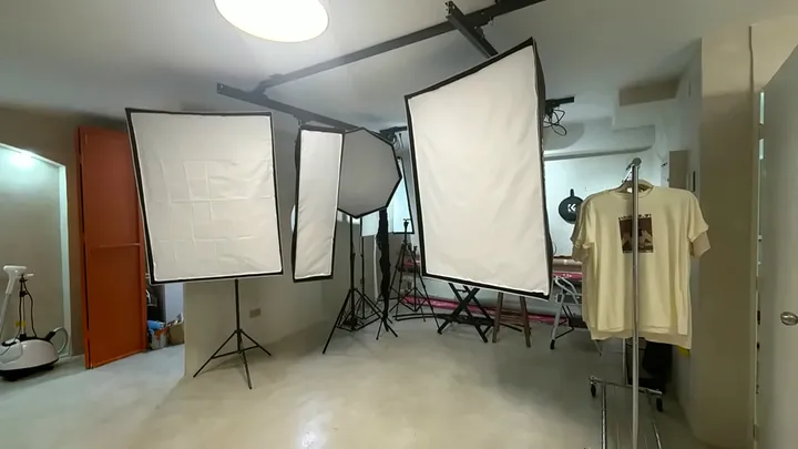 Sala principal con varios softbox, un perchero y una puerta terracota.